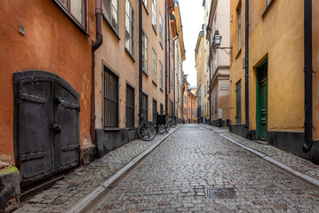 Obraz premium Sweden quaint cobblestone street in picturesque Gamla Stan, Stockholm's oldest neighborhood. Parked bicycles lean against the colorful plaster buildings. 