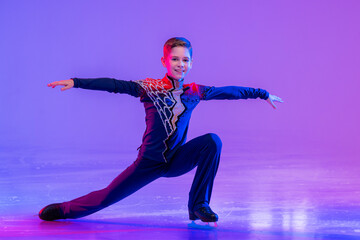 Boy figure skater skating on ice. With festive colored lilac lighting. © Maria Moroz