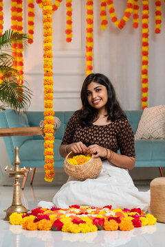 Young female model holding flower basket and making Onam pookalam, Happy Onam and Diwali festival concept image