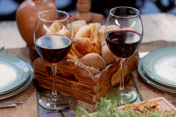 Glass of red wine, it shows a close-up of a glass of red wine sitting on a table, against a backdrop of greens and salad