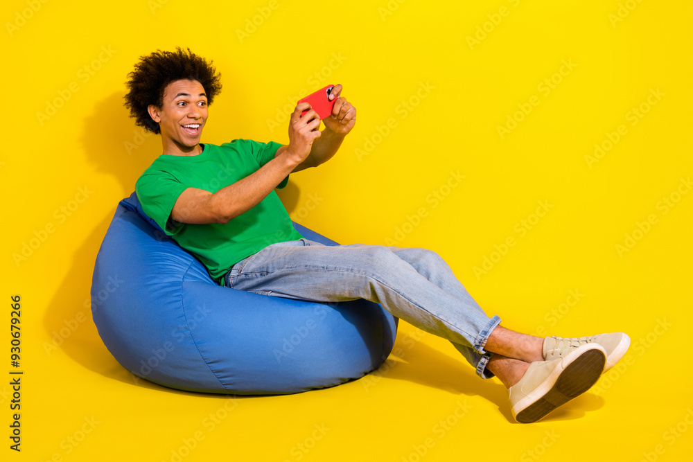 Wall mural Full length photo of cheerful positive guy dressed green t-shirt playing game modern device emtpy space isolated yellow color background