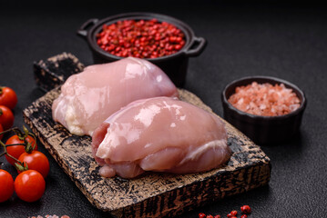 Fresh chicken fillet on a dark concrete table with spices and herbs