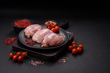 Fresh chicken fillet on a dark concrete table with spices and herbs