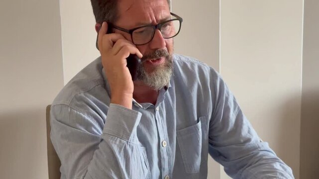 Busy mature man office worker manager consulting client by telephone checking information on laptop screen. Professional teleworker broker salesman offer goods services remotely using phone laptop