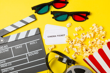 Tasty popcorn in buckets and cold cola drinks with cinema tickets, movie clapper and 3D eyeglasses...