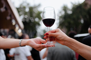 Moment of exchanging a glass of red wine in the open air