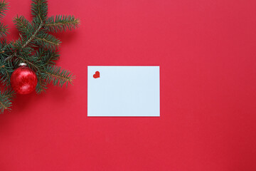 Christmas card with heart, with red ornament and pine branch.