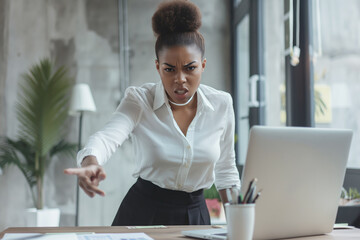 Angry businesswoman with a bun pointing and leaning over desk in a modern office. She is wearing a white blouse and black skirt, expressing intense frustration and authority