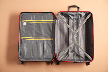 Open empty suitcase for travelling on beige background, top view