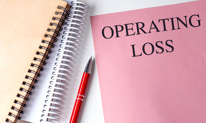 OPERATING LOSS text on pink paper with notebooks