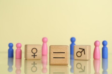 Gender equality concept. Wooden cubes with male and female figures on light yellow background,...