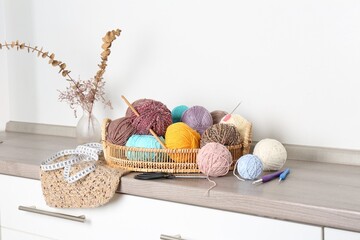 Different yarns, crochet hooks and other tools on wooden shelf