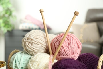 Colorful yarns and knitting needles on blurred background, closeup