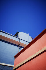 Vertical Low-Angle View of Colorful Blue and Pink Houses in Olbia, Sardinia, Framing a Vibrant Blue Sky