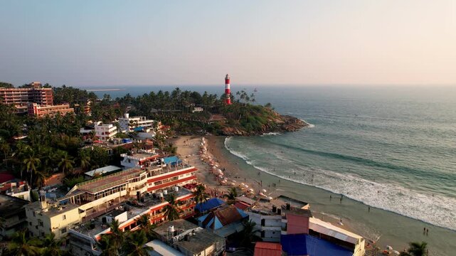 Lighthouse tower on a rocky coastline at sunset, Aerial View. Kovalam Beach whith Lighthouse in India, Kerala