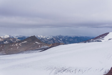 view of the high mountains above the clouds from the glacier on the slope of Mount Elbrus