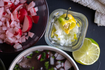 refractario de vidrio con chile habanero entero y picado con cebolla y limón junto a plato con...