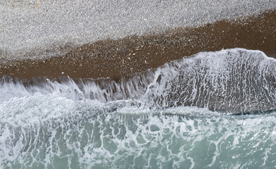 Windy waves crashing on a pebble beach. Drone aerial of stormy sea