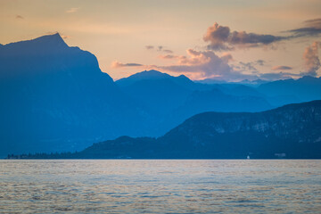 Lake Garda with mountains in background at sunset, view from Lazise town shore, Italy, Europe.