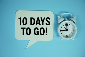 10 Days to go text on speech bluble with alarm clock top view on blue background
