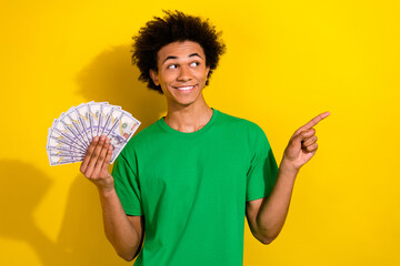 Photo of handsome good mood guy wear green t-shirt rising cash fan showing emtpy space isolated...