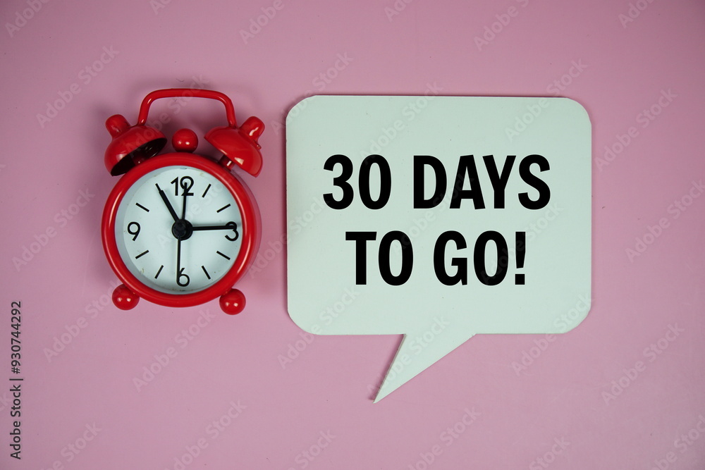 Poster 30 days to go text on speech bluble with alarm clock top view on pink background