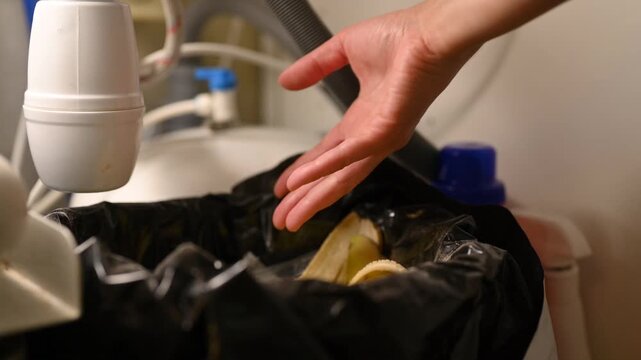 Assorted unlabeled batteries are thrown into the household waste bin under the kitchen sink