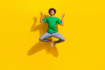 Obraz premium Full length photo of funky cool guy dressed green t-shirt jumping high enjoy yoga emtpy space isolated yellow color background