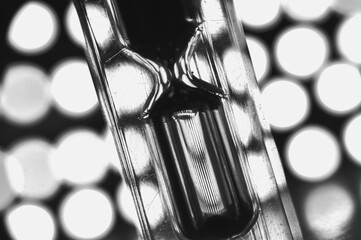 A black-and-white hourglass close-up measuring time with flowing sand transparent glass