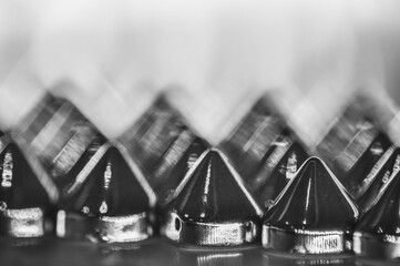 Close-up macro of sewing studs arranged in symmetrical rows in black and white abstraction abstract