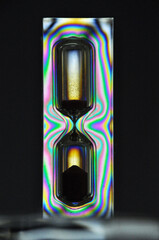 A colorful rainbow hourglass measuring time against a black background minutes