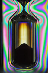 A colorful rainbow hourglass measuring time against a black background minutes