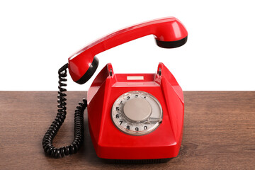 One red telephone with handset on wooden table against white background