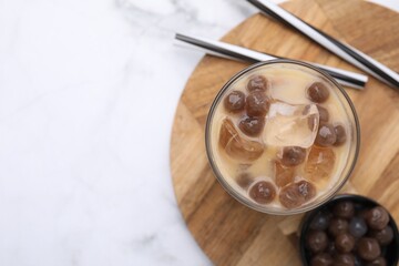 Tasty milk bubble tea in glass, tapioca pearls and straws on white marble table, top view. Space for text