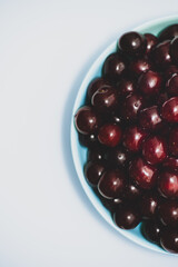 A full plate of ripe red cherries on the white background
