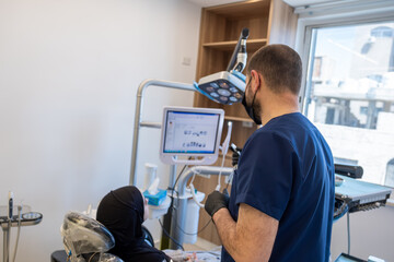 dentist displaying tooth scans for the female muslim patient and talking about her situation for treatment later on