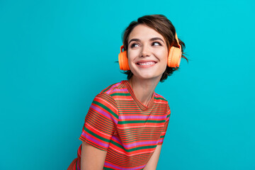Photo of satisfied cute woman dressed striped t-shirt in headphones look at playlist empty space isolated on turquoise color background