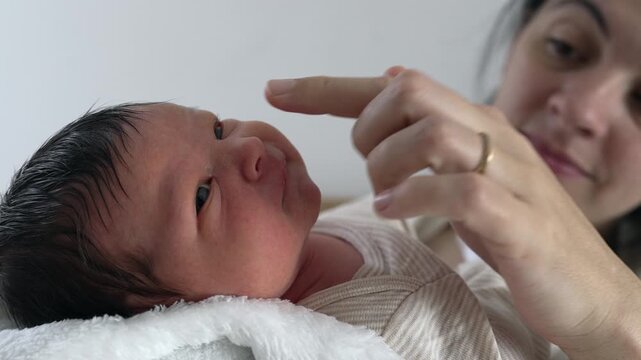 Mother gently removes nasal mucus from her newborn baby&rsquo;s nose, demonstrating tender care and attentiveness, the nurturing bond between mother and child
