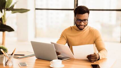 Fototapeta premium Checking Instructions. Confident black lawyer in glasses reading paper documents in modern office, panorama, copyspace