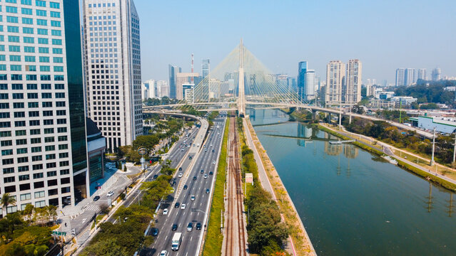 Foto a&eacute;rea da Ponte Estaiada com vista para a Marginal Pinheiros e o Rio Tiet&ecirc; em um dia ensolarado, destacando a beleza da paisagem urbana e a arquitetura moderna da ponte