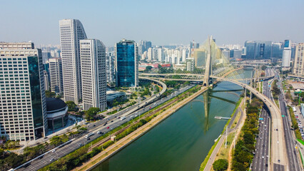 Fototapeta premium Foto aérea da Ponte Estaiada com vista para a Marginal Pinheiros e o Rio Tietê em um dia ensolarado, destacando a beleza da paisagem urbana e a arquitetura moderna da ponte