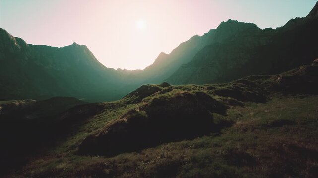 The sun shines brightly over a rugged mountain range, illuminating the peaks and valleys below.