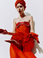 Woman in elegant red dress and high heels posing for fashion magazine photo shoot in studio setting