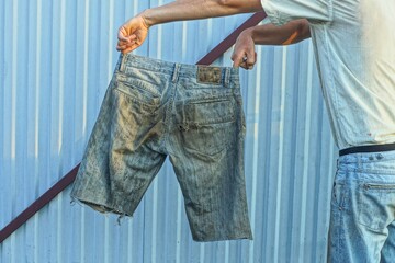 some dirty old denim men's blue worn torn with back pockets stylish fashion shorts in hands near...