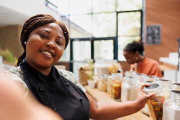 Female blogger creates eco friendly content promoting sustainable, plastic free shopping and healthy living. Vendor filming with smartphone, showcasing trendy tips for low carbon footprint lifestyle.