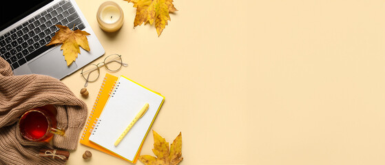 Composition with modern laptop, notebooks, cup of tea and autumn leaves on color background