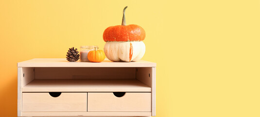White table with pumpkins near orange wall, closeup