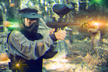 Woman targeting with paintball gun to eliminate enemies on battlefield. Markswoman shooting with...