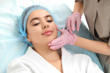 Cosmetologist giving injection to young woman in beauty salon, closeup