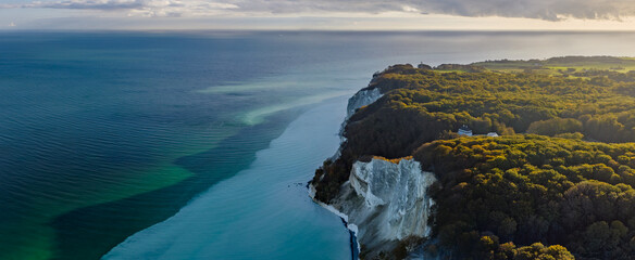 Aerial view of white cliffs, dense forest and building in classic Scandinavian architectural style...